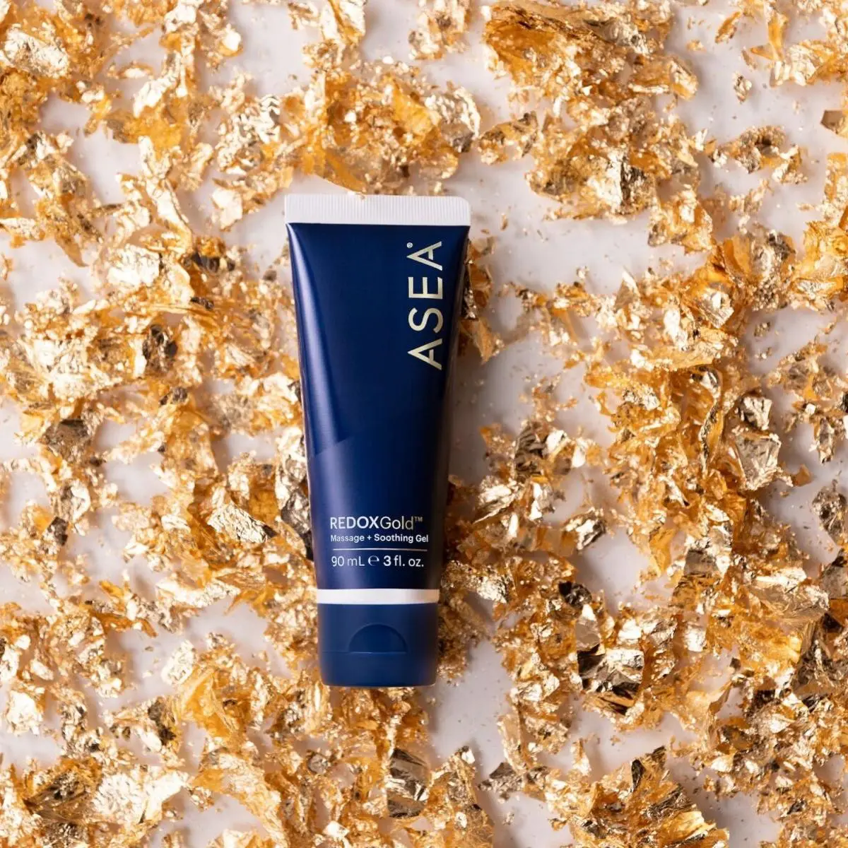 A bottle of asea redox gold on a background of gold flakes